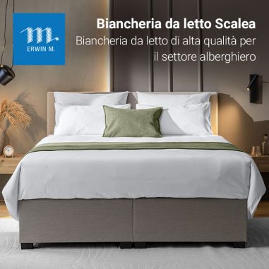 Biancheria da letto Scalea presentata su un letto boxspring in una camera d’hotel
