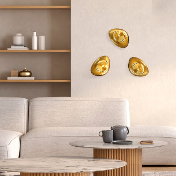 Soggiorno arredato in stile scandinavo con lampade da parete dorate dalle forme organiche