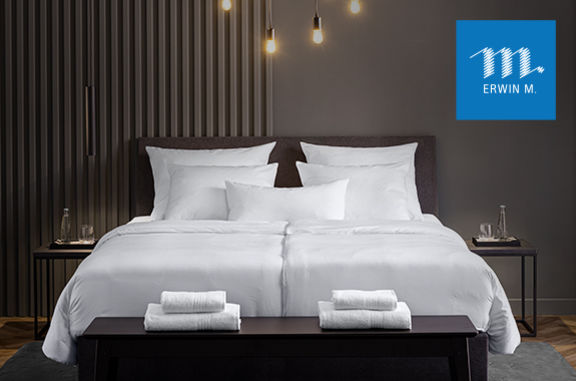 Ein Bett in einem Hotelzimmer mit Bettwäsche und Handtücher von ERWIN M.