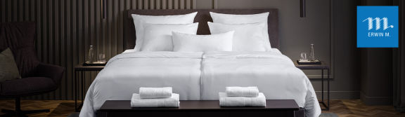 Ein Bett in einem Hotelzimmer mit Bettwäsche und Handtücher von ERWIN M.